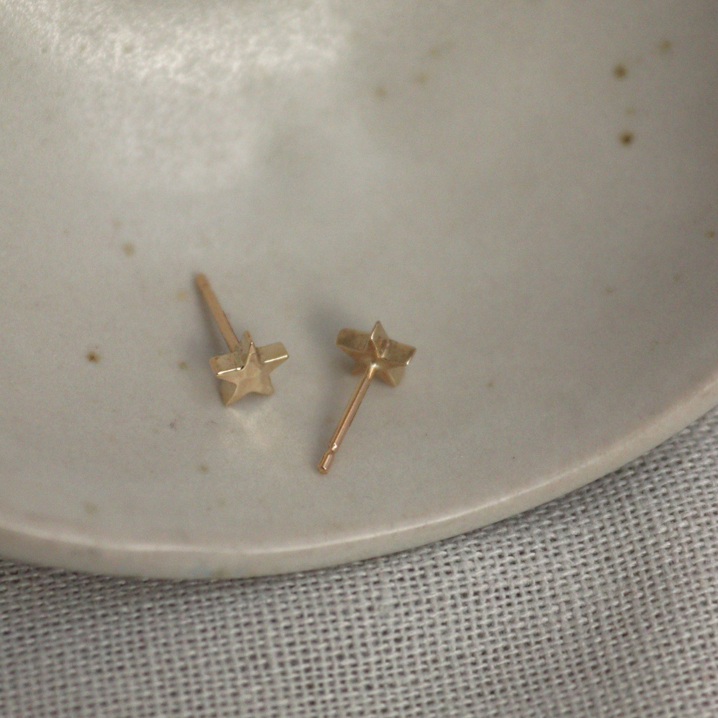 9ct yellow gold star studs on a ceramic bowl showing the ear pin.