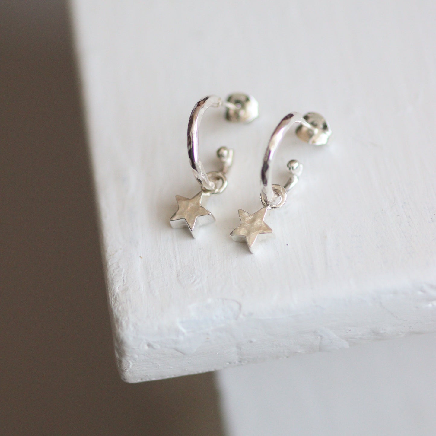 Silver star-shaped earrings on a white surface