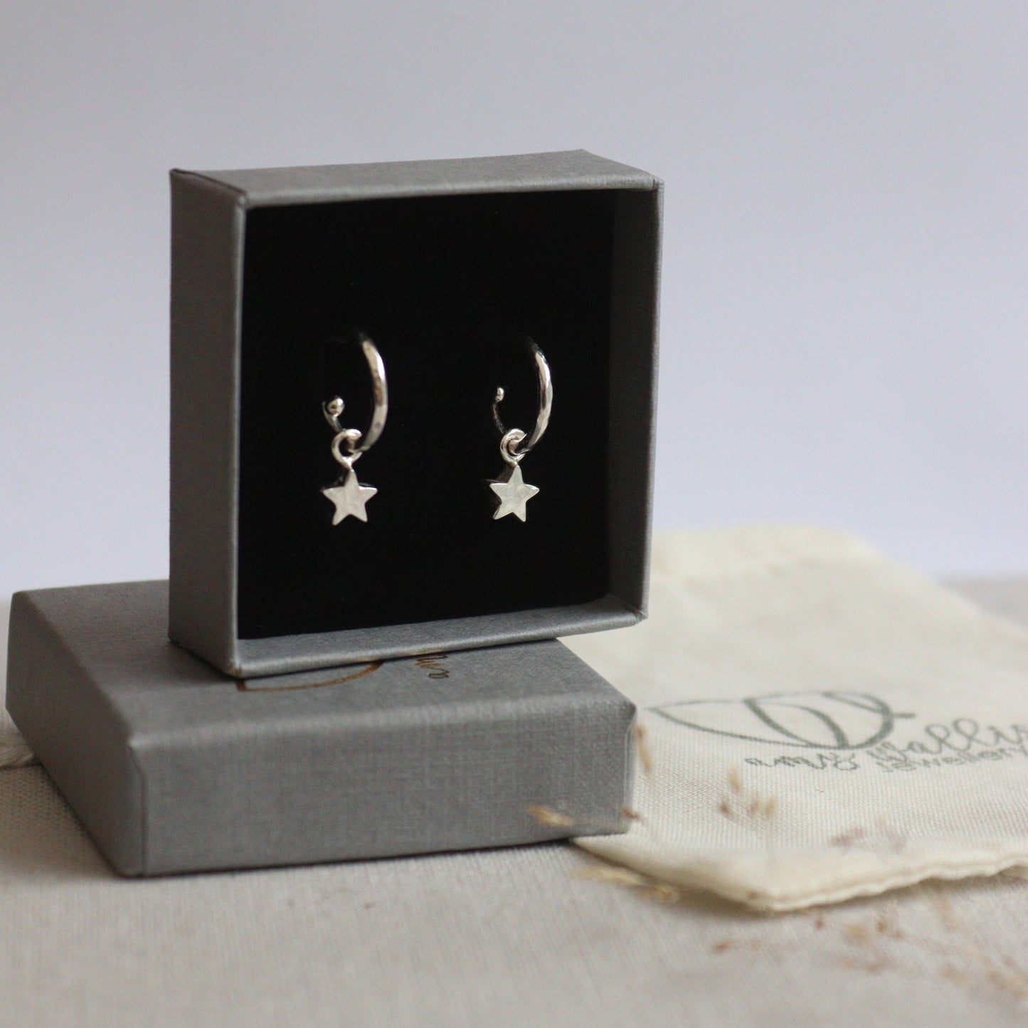 Pair of star-shaped earrings in a gray box on a textured surface