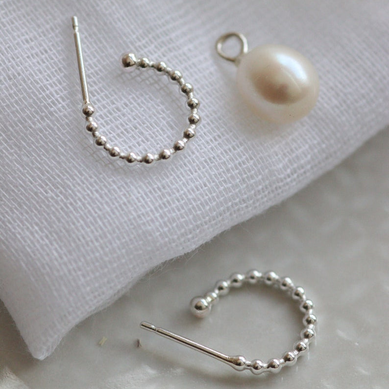 Silver and pearl hoop earrings with removable drops on a muslin background.