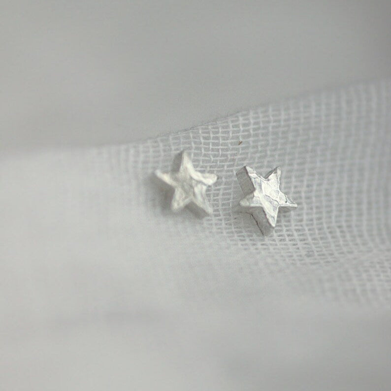 Side view of chunk silver star studs with a hammered texture. Threaded through fine muslin.
