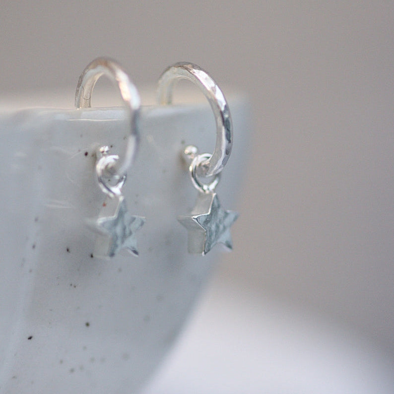 Silver star earrings on a white textured surface