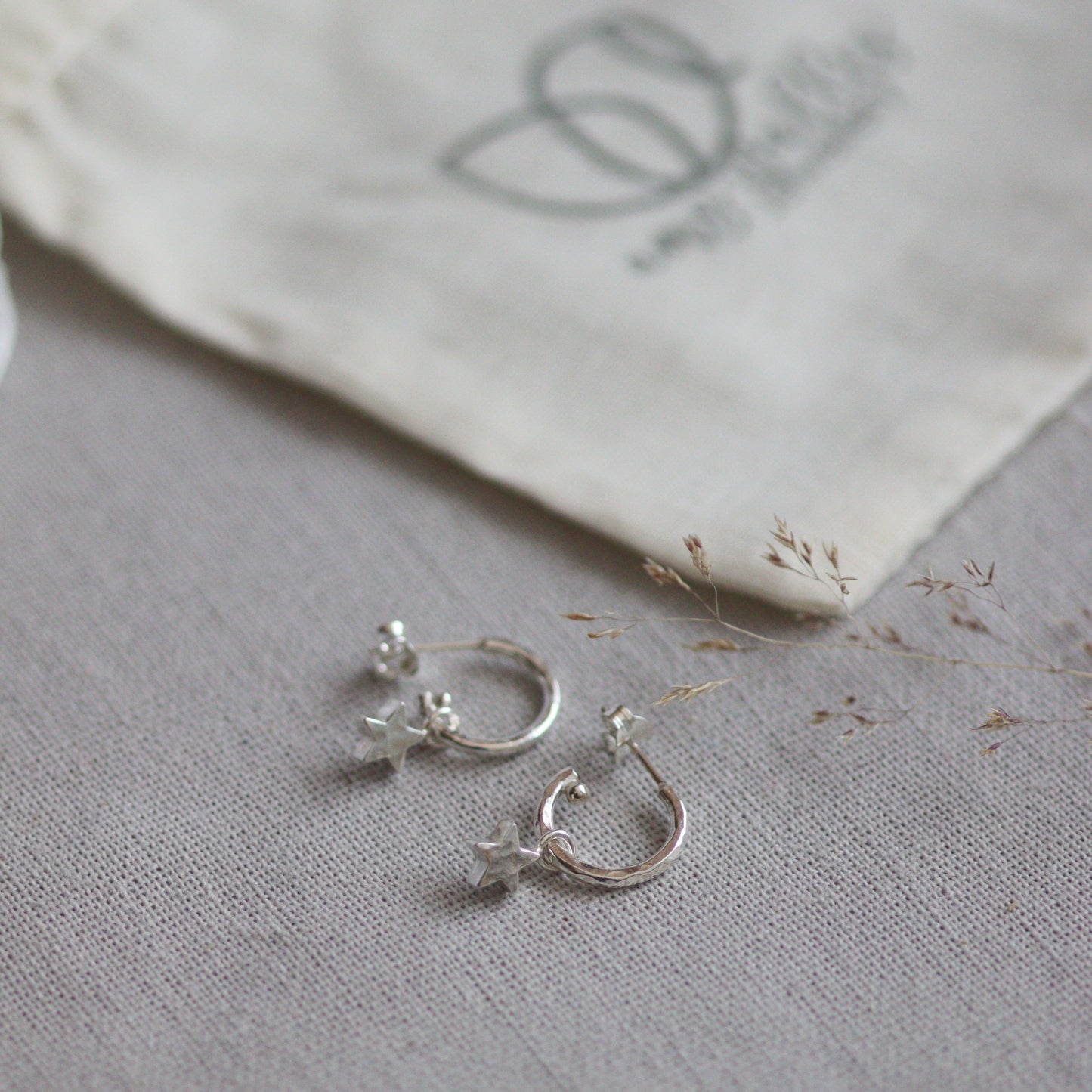 Silver star earrings on a textured gray surface with a white fabric background