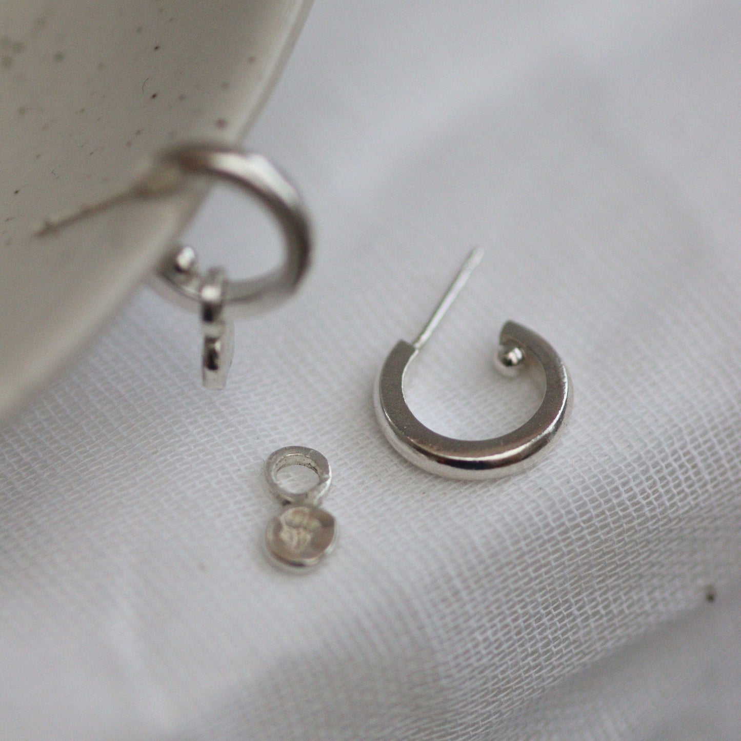 Silver huggie hoops, one with the little confetti dangle on and one showing they can be worn plain without the drop.