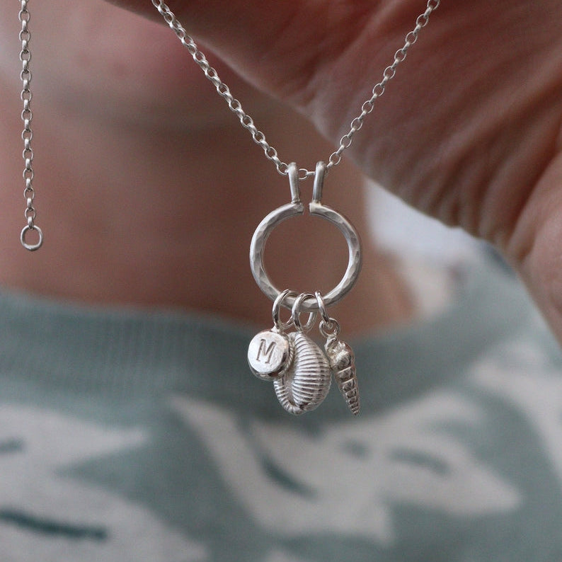 A silver keeper necklace for wearing charms all together. This is shown with silver charms including silver seashells.