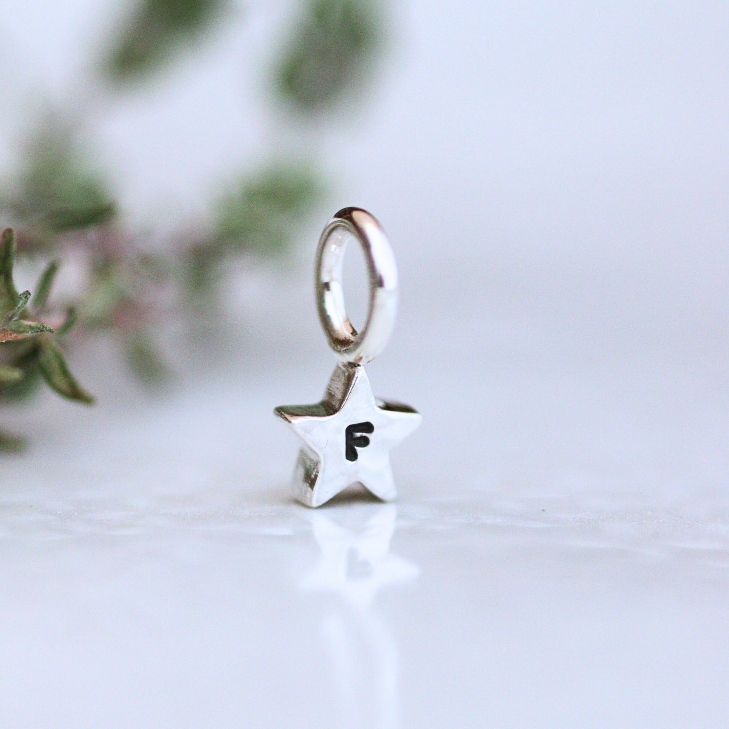 Silver star-shaped charm with letter 'F' personalisation on a light background