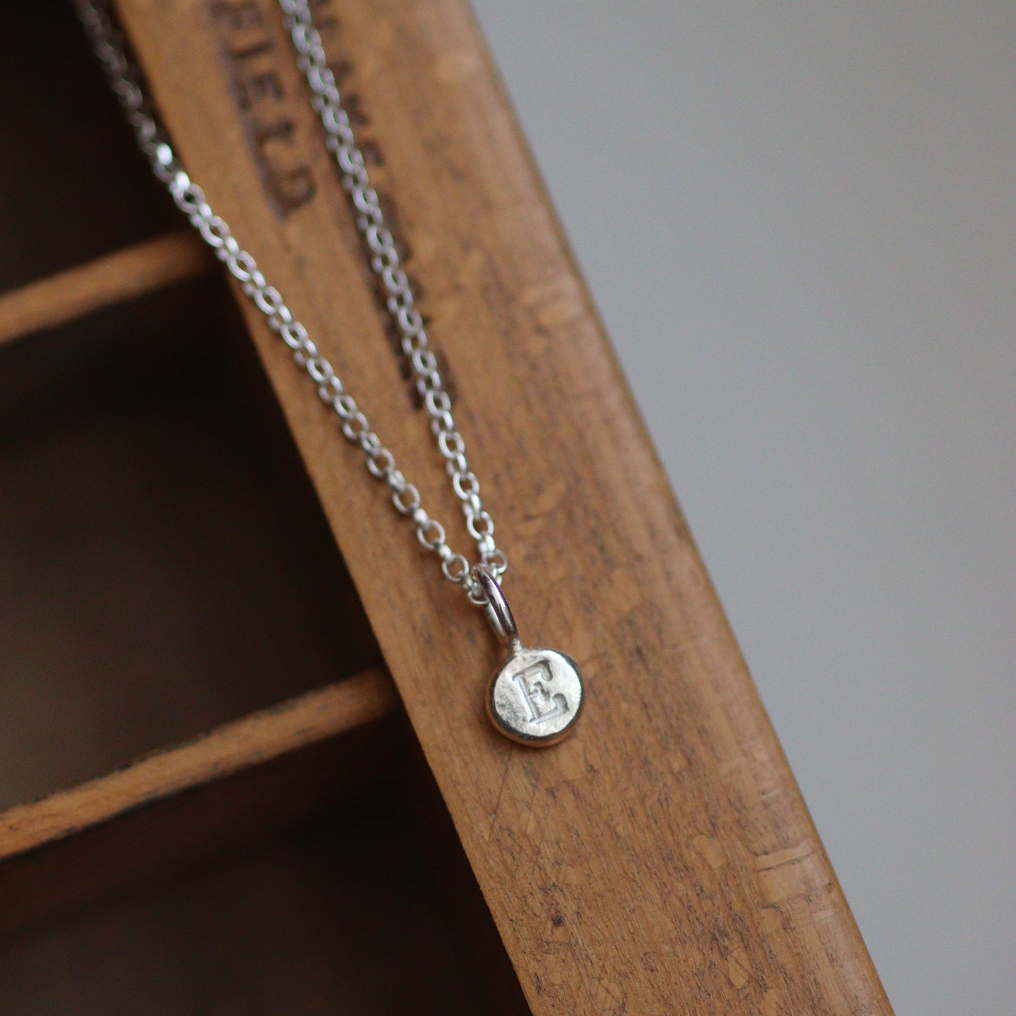 Silver chain with a personalised round pendant on a wooden surface