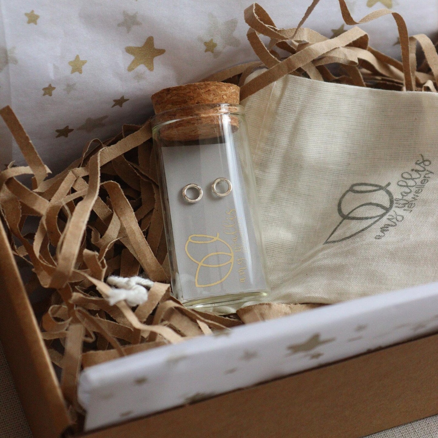 silver hugs and kisses earrings in a glass bottle in a postal box with cotton pouch and tissue paper.