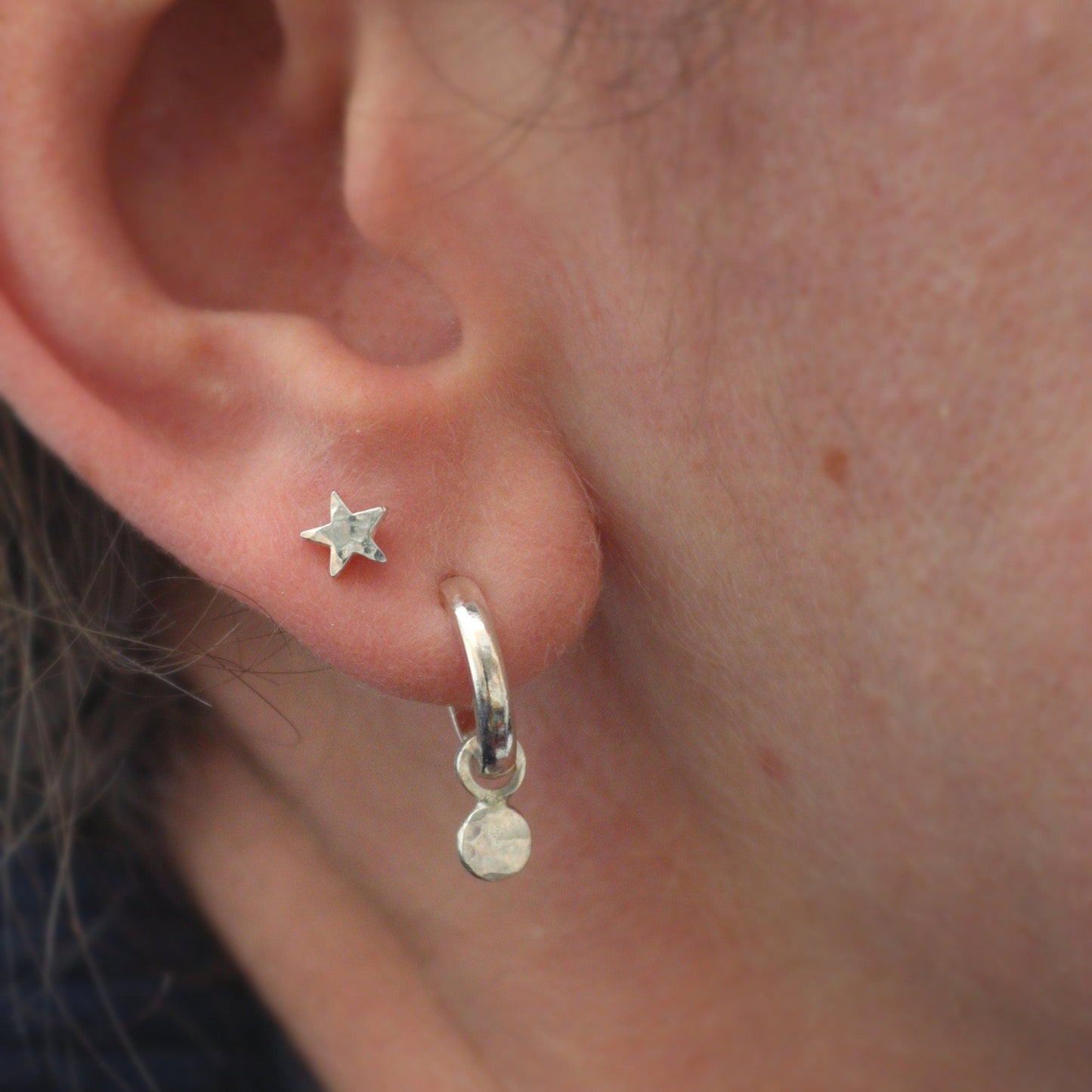 tiny silver star studs being worn with the chunky huggie hoops.