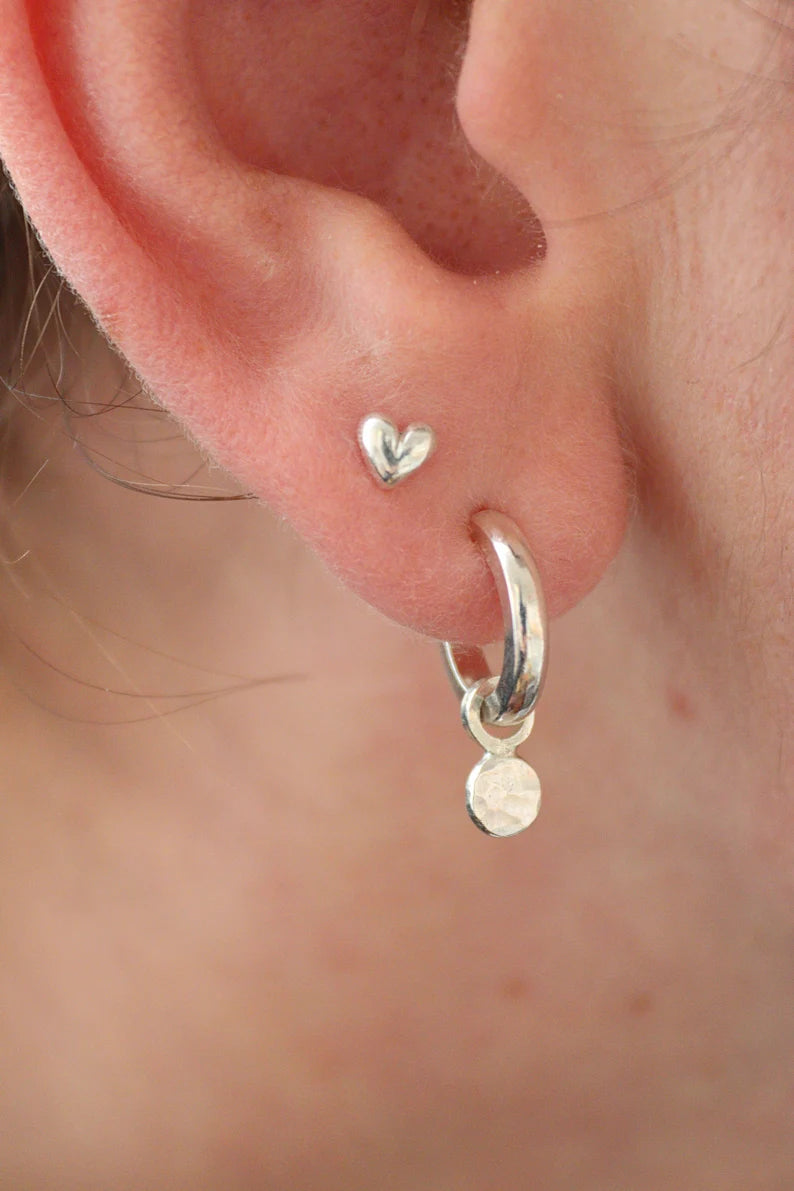 3D Silver heart studs in the second piercing in an ear