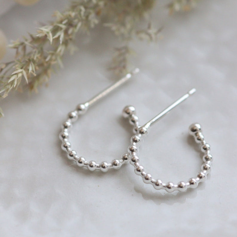 Silver hoop earrings with beaded design on a light background