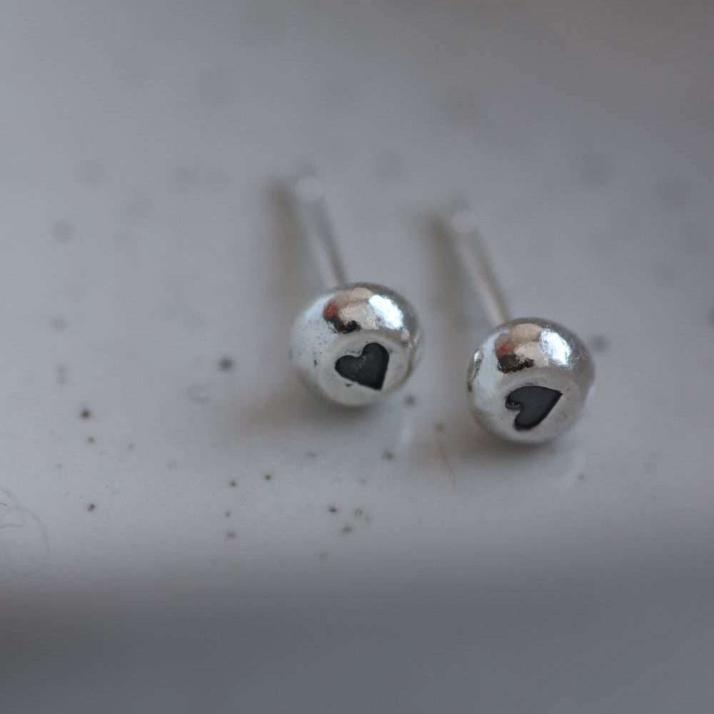 silver stud earrings with a heart stamp in the middle in contrasting black.