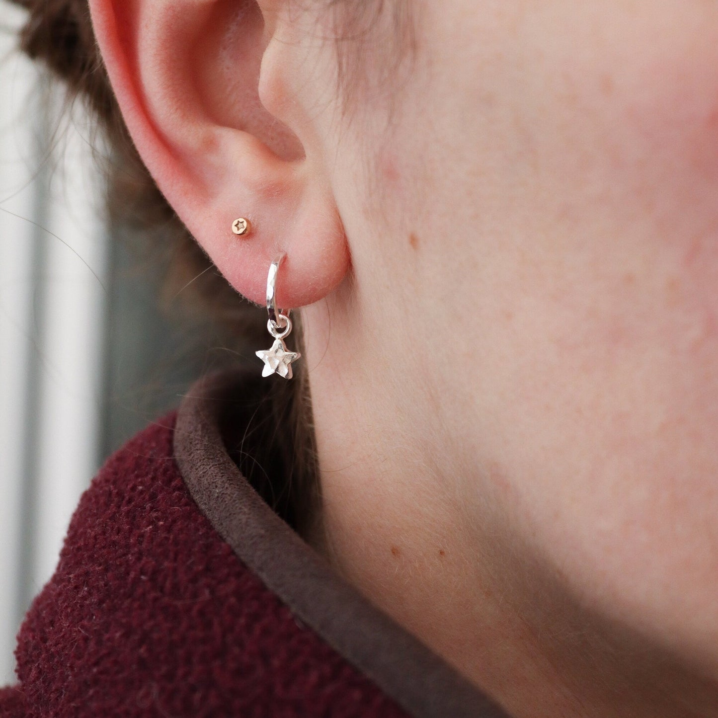 Silver star huggie earrings being worn by a model.