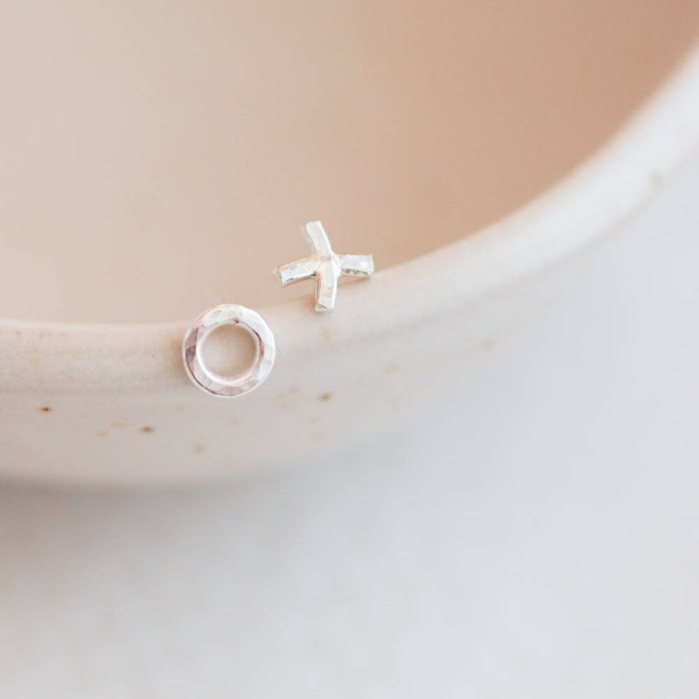 Silver hammered hug and kiss stud earrings on a bowl lip.
