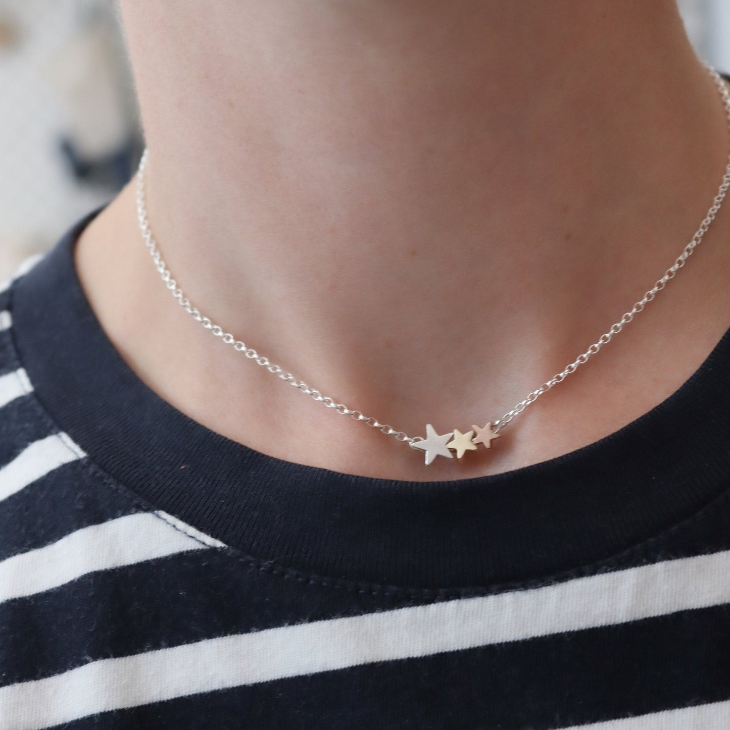a necklace with 3 star shape beads on a fine chain