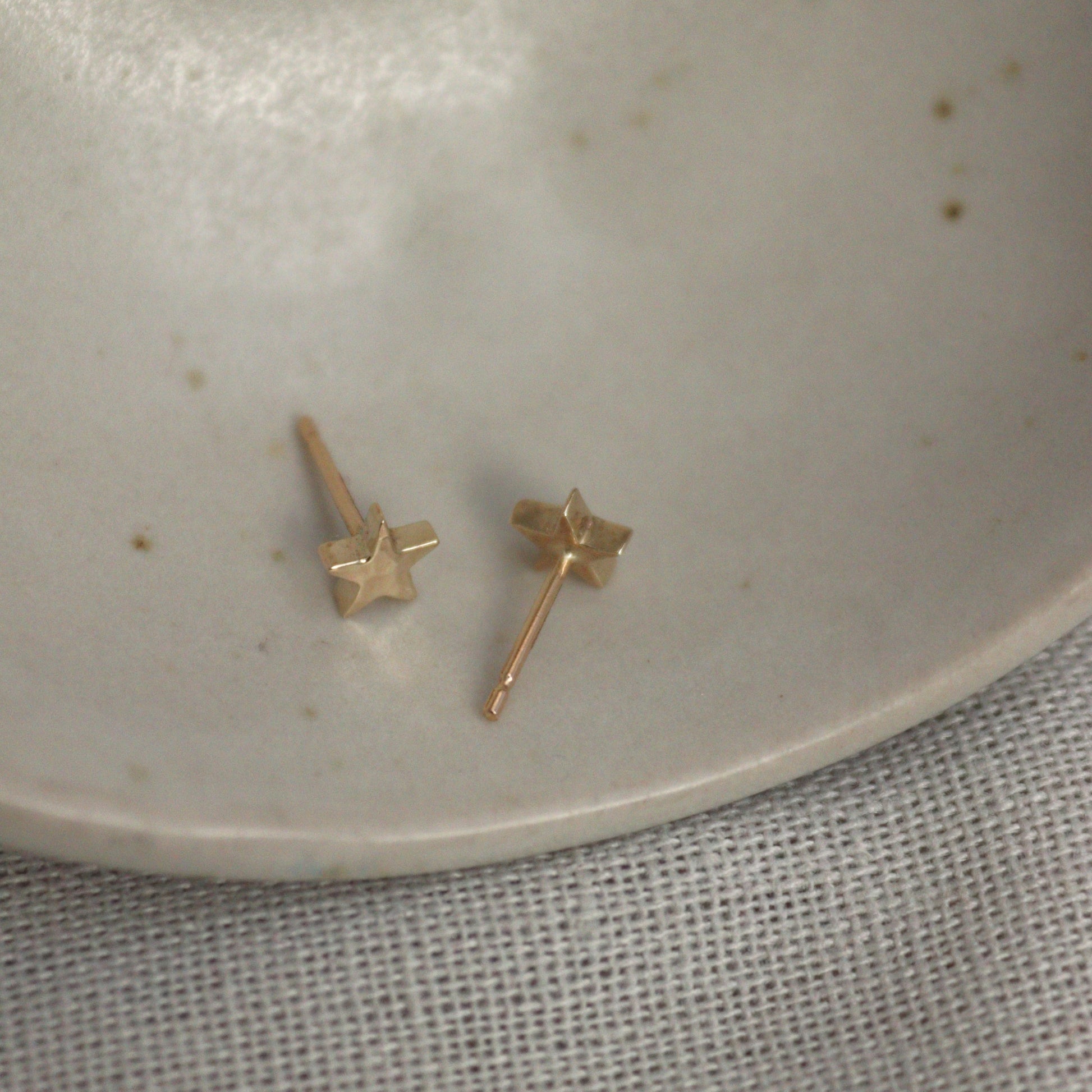 9ct yellow gold star studs on a ceramic bowl showing the ear pin.