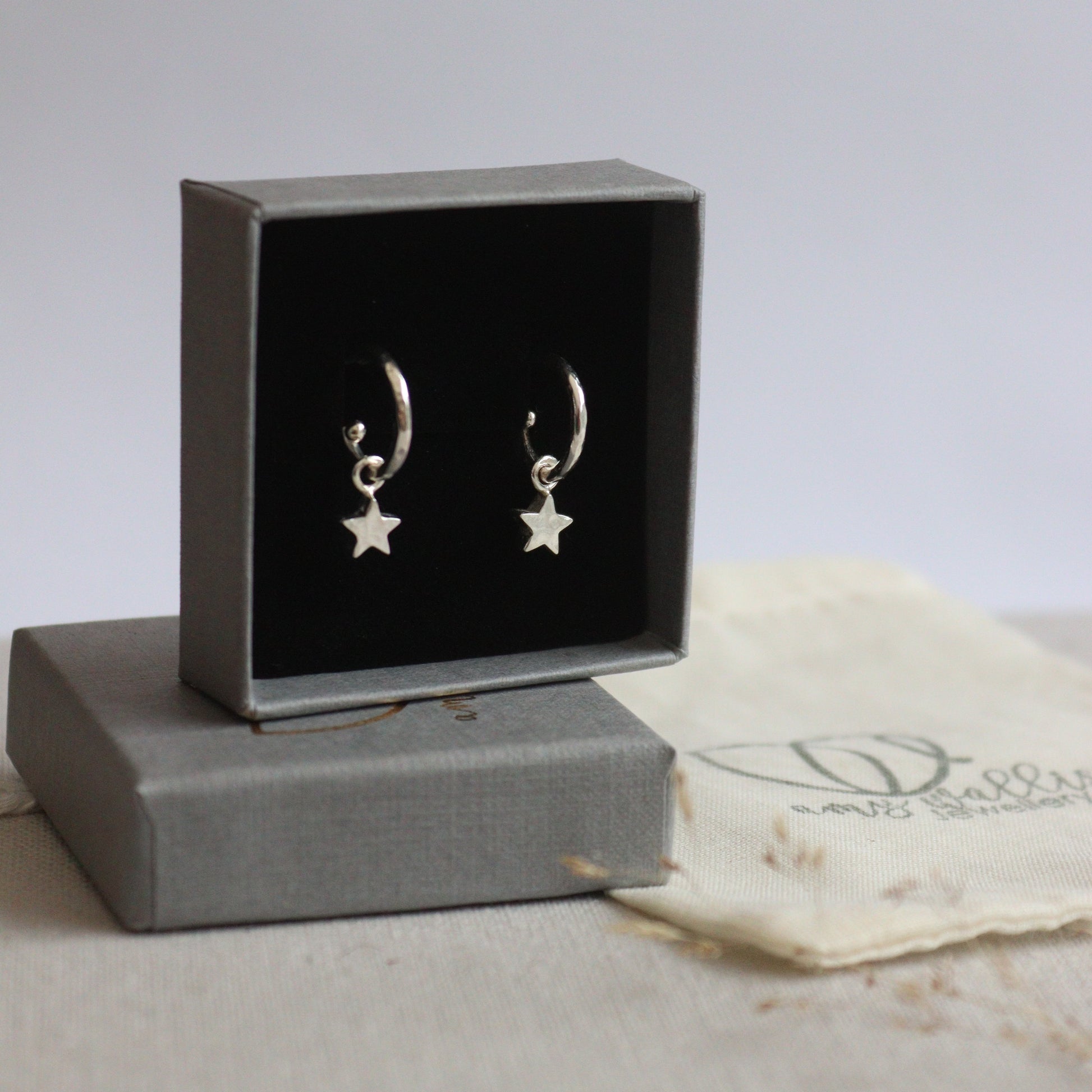 Pair of star-shaped earrings in a gray box on a textured surface
