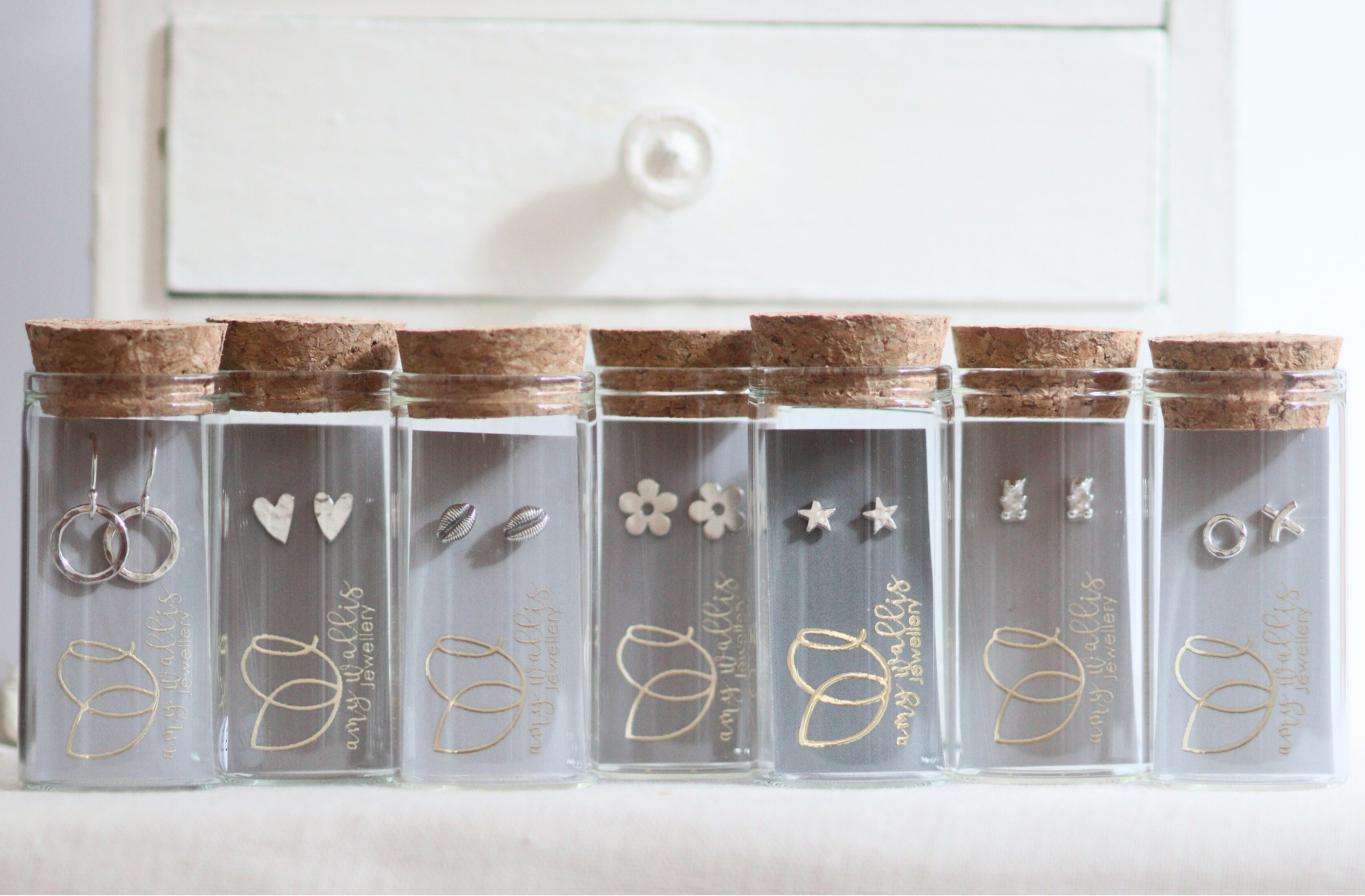 Bottles with silver earrings on branded cards inside.