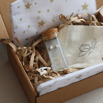 A Glass bottle with silver stud earrings inside , in a gift box with decorative tissue. 