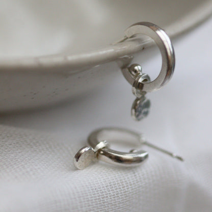 Silver huggie hoops with confetti like circular hammered drops.
