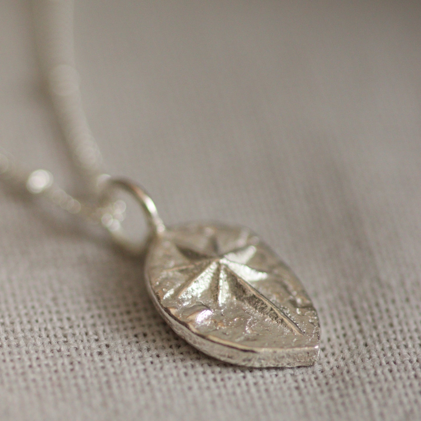 The detail of a hand cast solid silver North Star pendant. You can see the unique texture created by the casting process which is catching the light.