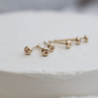Pair of gold stud earrings with star design on a white surface