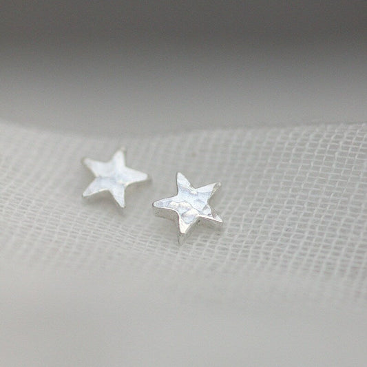 Tiny hammered silver star stud earrings threaded through fine muslin.