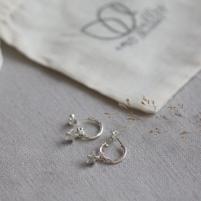 Silver star earrings on a textured gray surface with a white fabric background