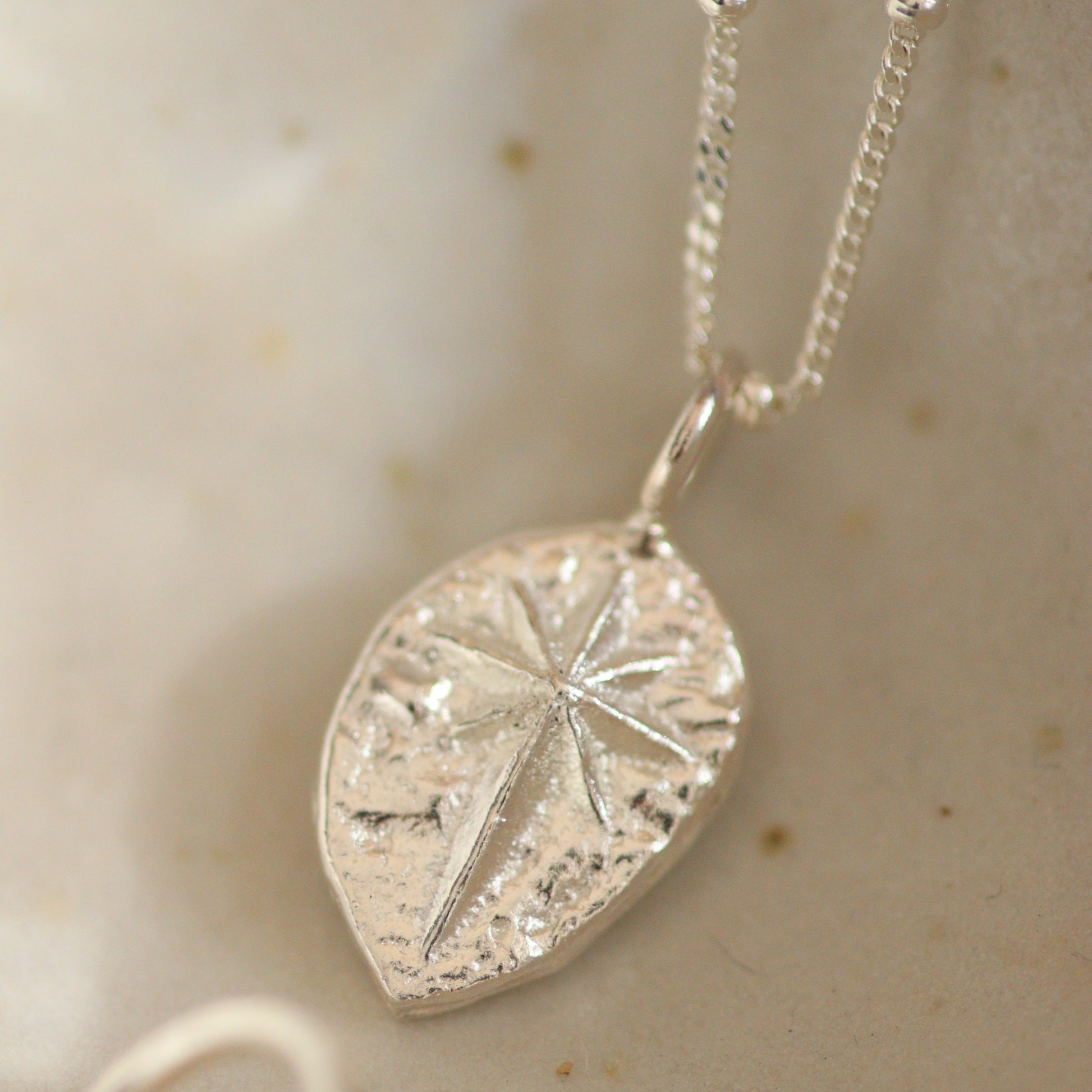 a silver north star pendant on a beaded satellite chain which is also bright silver.
