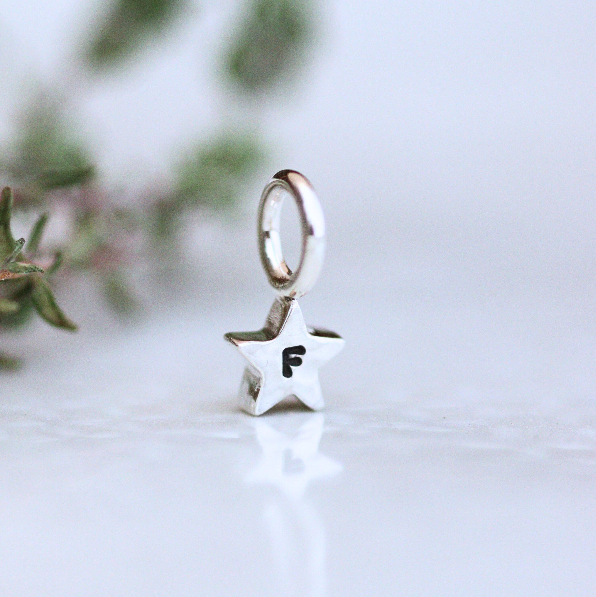 Silver star-shaped charm with letter 'F' personalisation on a light background