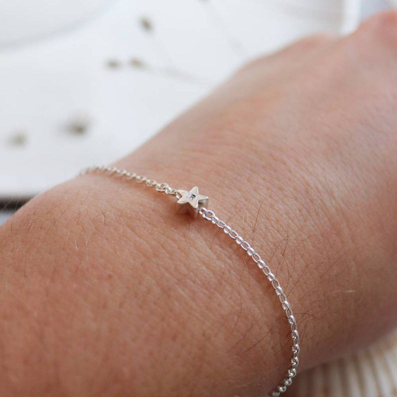 Silver bracelet with an initial personalisation on a wrist with a blurred background