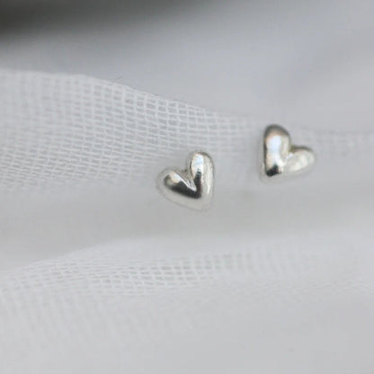 Tiny 3D Silver hand carved heart studs in a ine white fabric
