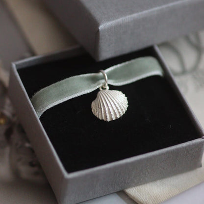Silver cockle shell pendant in a grey jewellery box with a green velvet ribbon