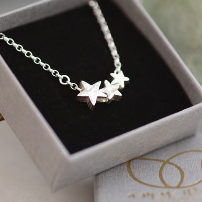 Silver star necklace in a branded grey box on a light surface