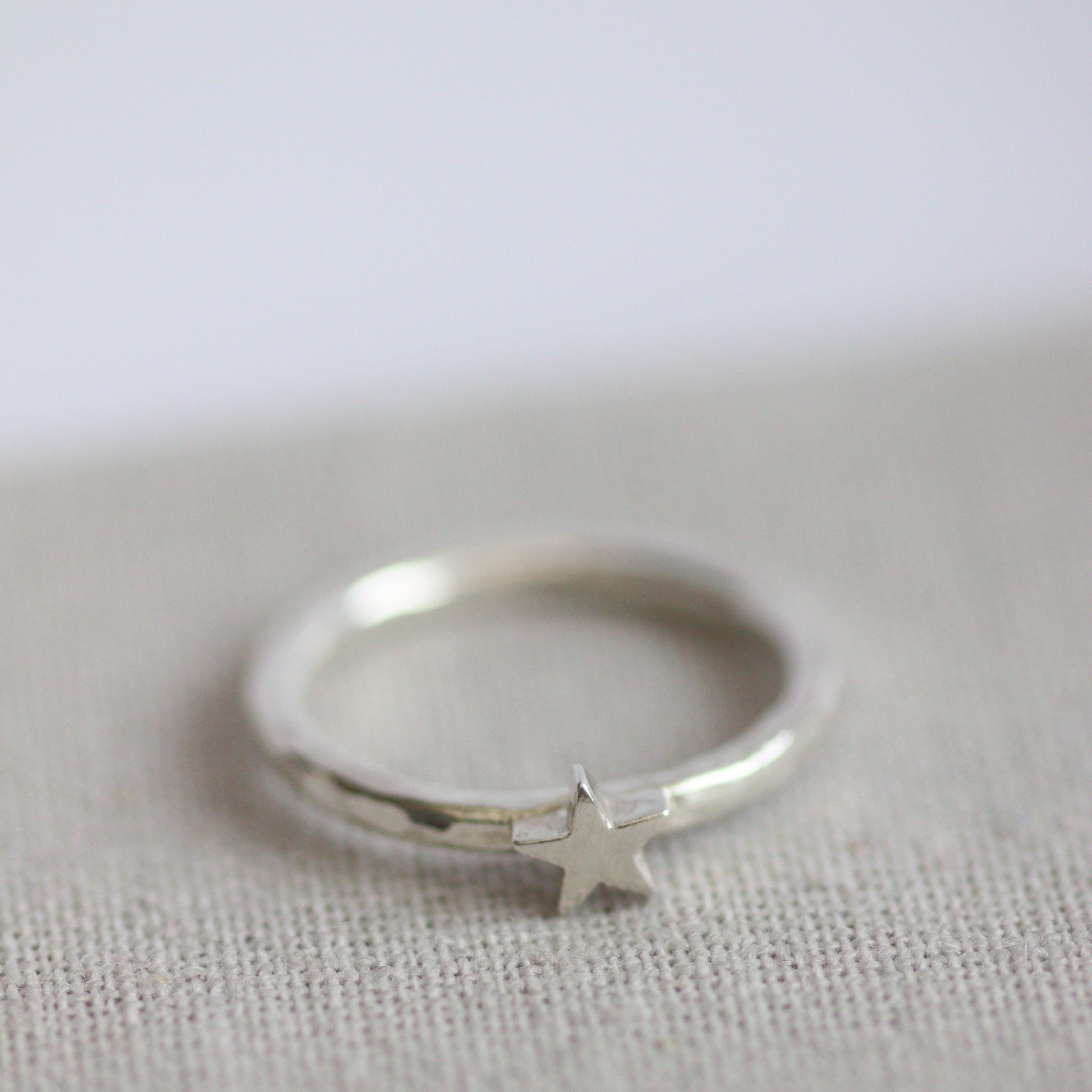 Silver ring with a star-shaped charm on a textured grey background