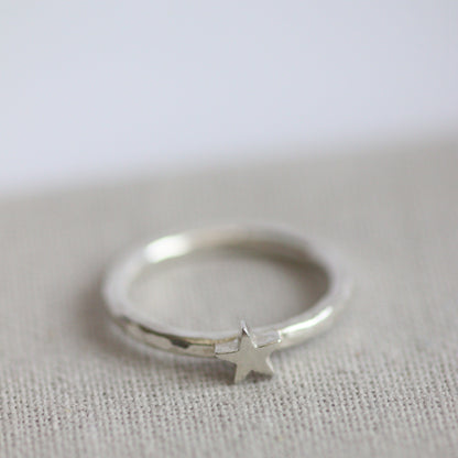Silver ring with a star-shaped charm on a textured grey background