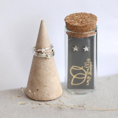 Cork lidded glass tube with silver star shaped studs inside and silver star stacking rings on a ring cone.