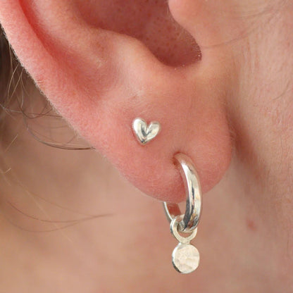3D Silver heart studs in the second piercing in an ear 