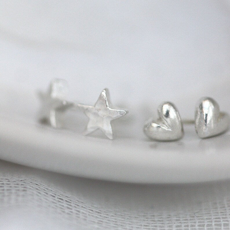 silver heart studs shown next to similar scale tiny silver star studs