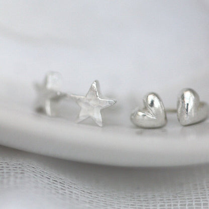 silver heart studs shown next to similar scale tiny silver star studs