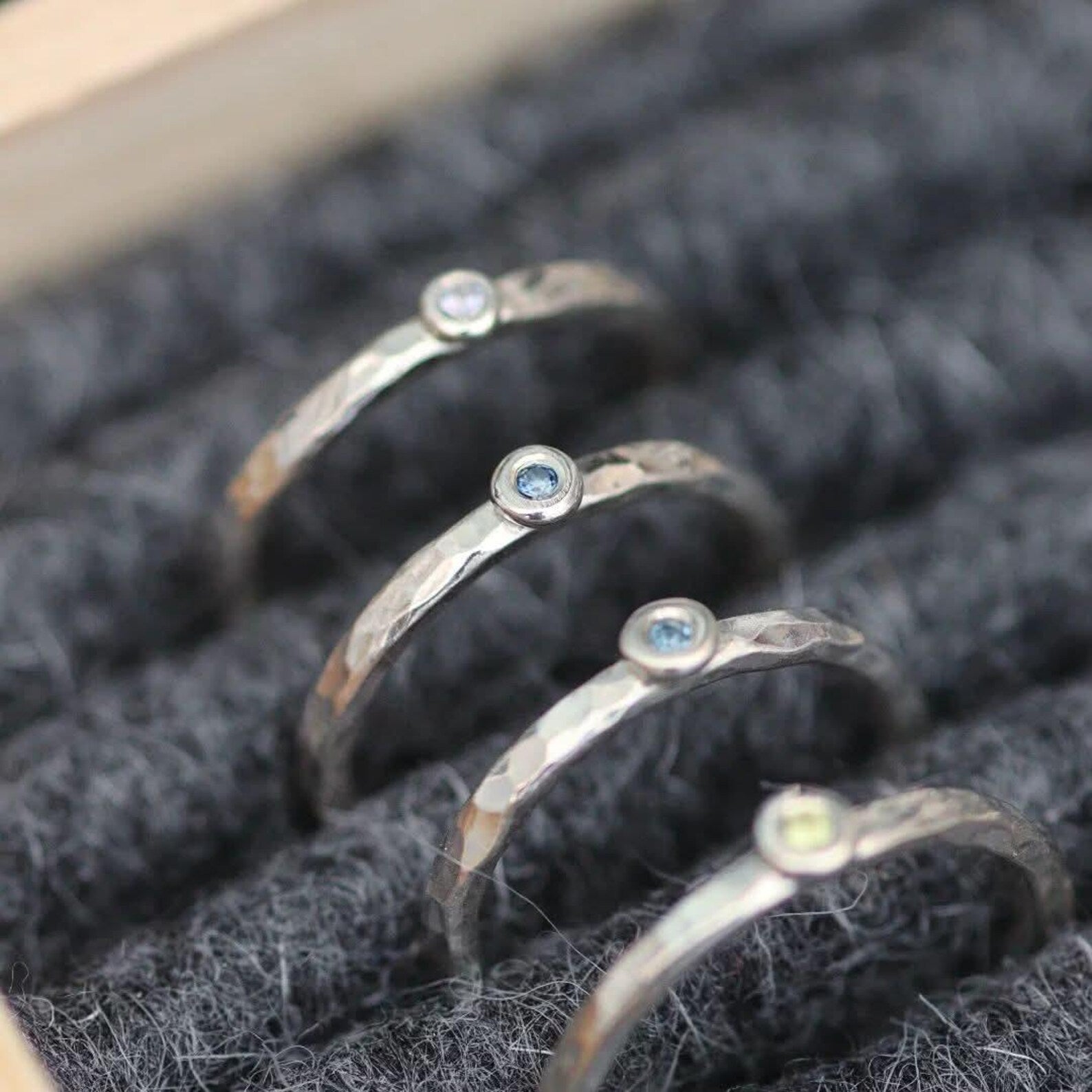 Set of silver rings with gemstones on a textured gray felt surface
