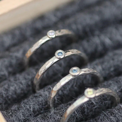 Set of silver rings with gemstones on a textured gray felt surface