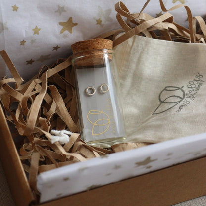 silver hugs and kisses earrings in a glass bottle in a postal box with cotton pouch and tissue paper.