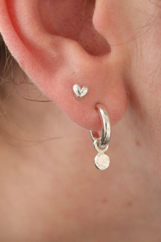 3D Silver heart studs in the second piercing in an ear 