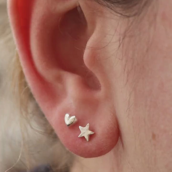 Silver heart and star studs shown in an ear from all angles