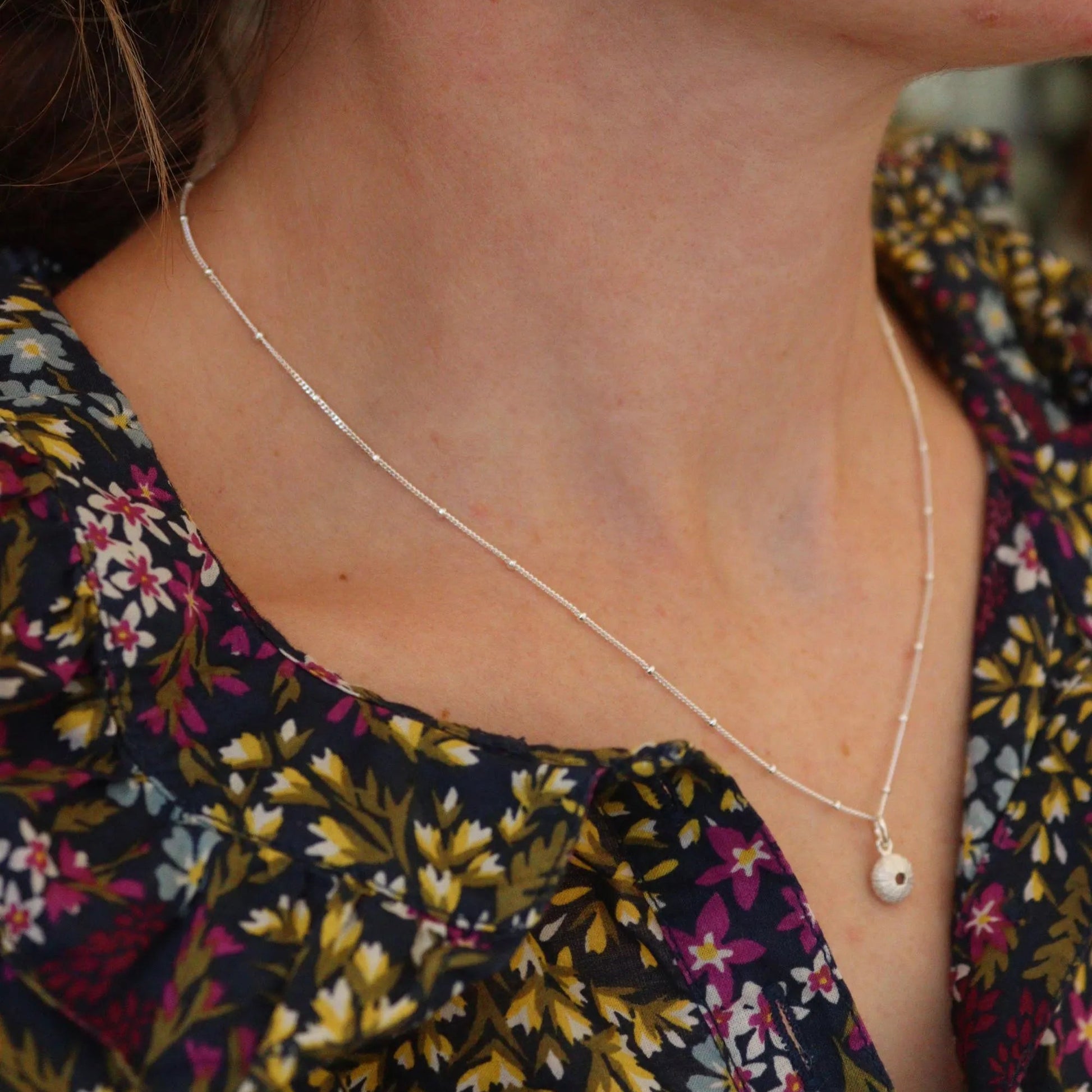 silver sea urchin jewellery being worn on a model wearing seasalt cornwall floral blouse