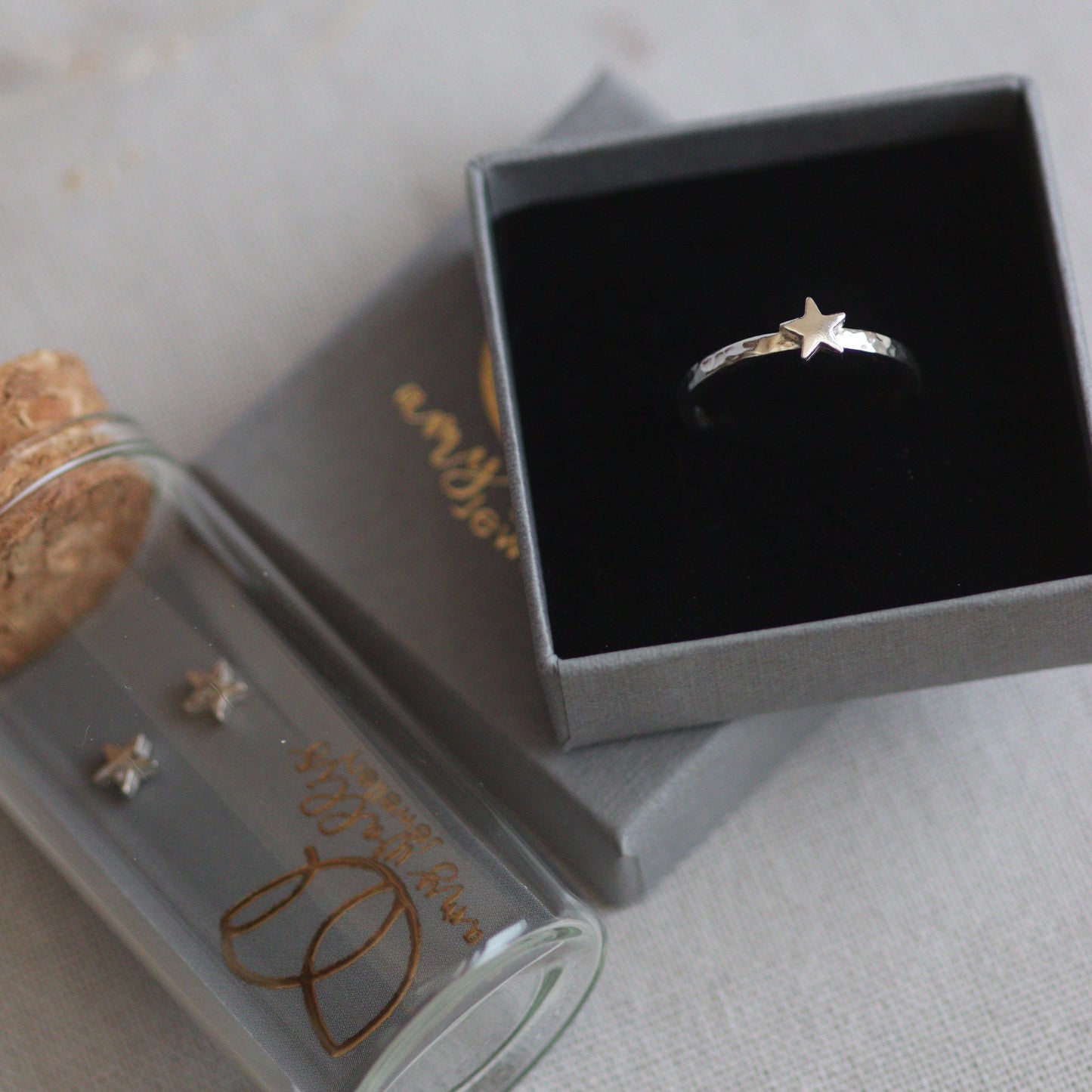 Silver star ring in a ring box and silver star stud earrings in a glass tube.