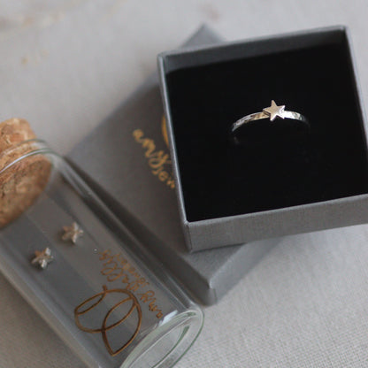 Silver star ring in a ring box and silver star stud earrings in a glass tube.
