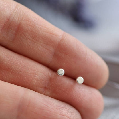 3mm recycled silver tiny dot stud earrings shown in a hand