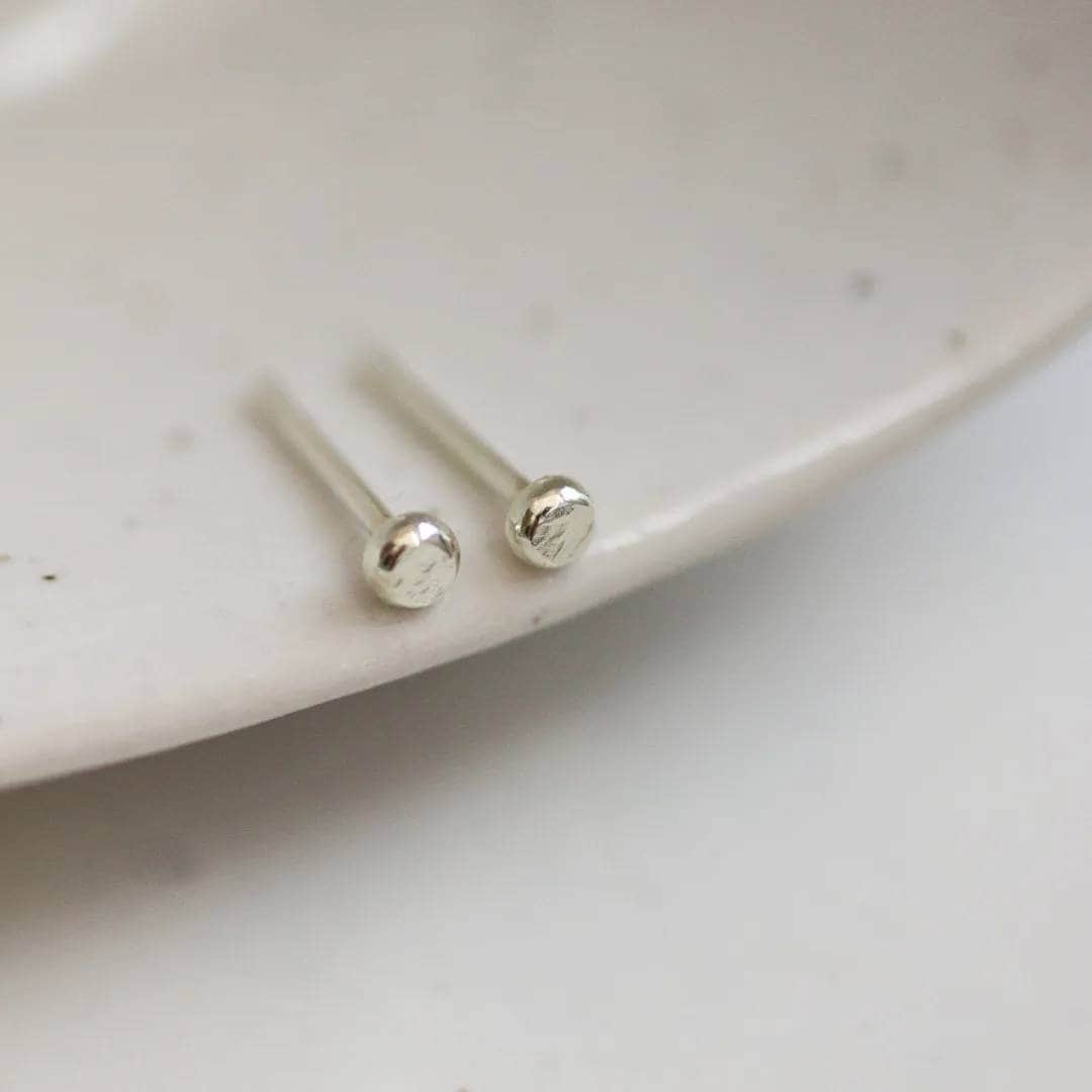 Tiny 9ct white gold dot stud earrings on the edge of a dish
